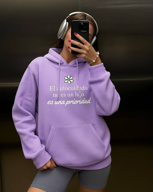 Mujer usando hoodie NARA “El autocuidado no es un lujo”, ambiente acogedor – imagen 2